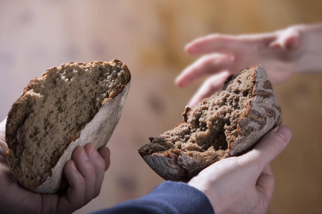 Jemand teilt ein Brot und gibt eine Hälfte weiter