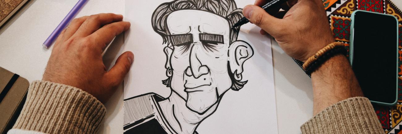 Zwei Hände zeichnen eine Karikatur auf ein Blatt Papier