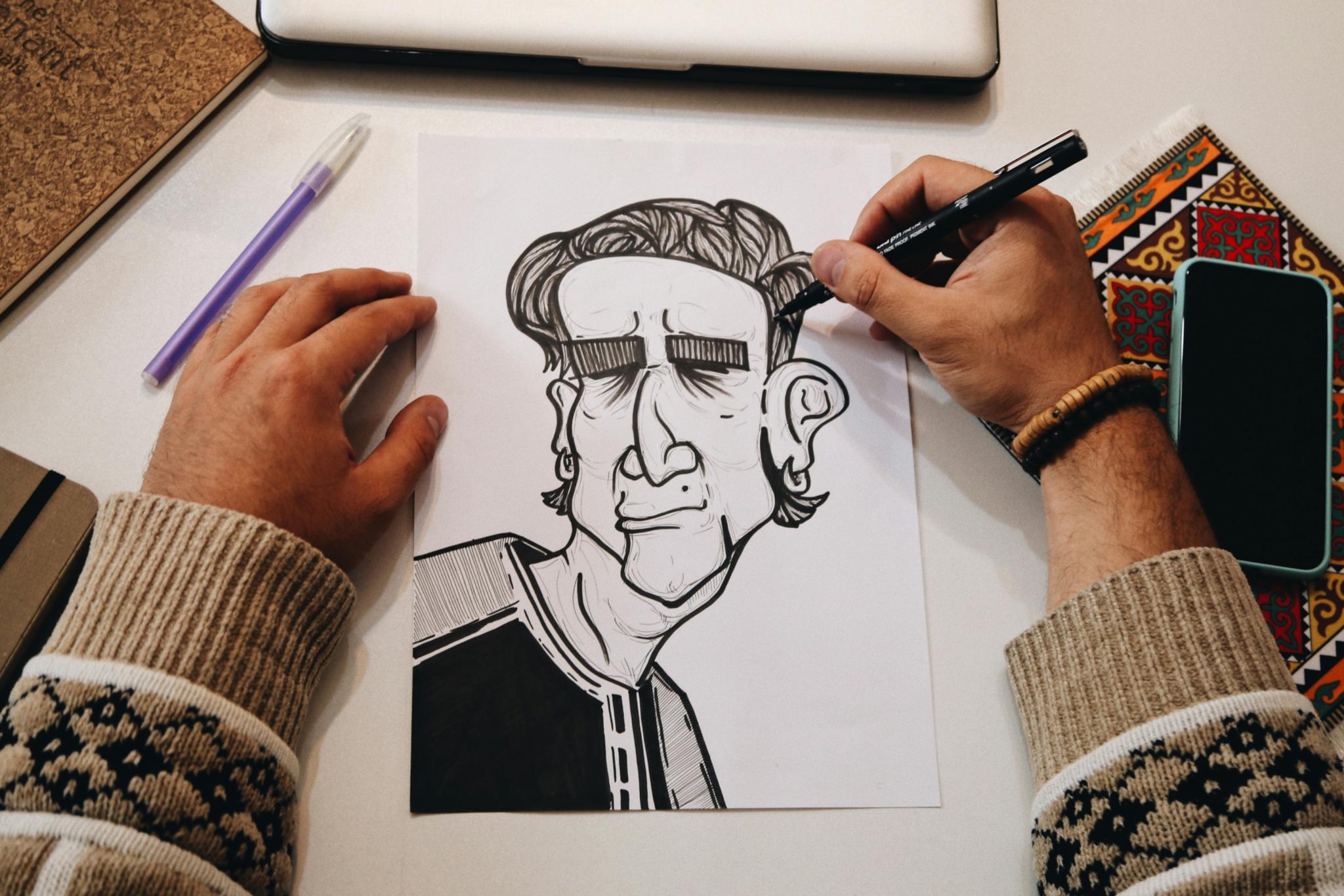 Zwei Hände zeichnen eine Karikatur auf ein Blatt Papier