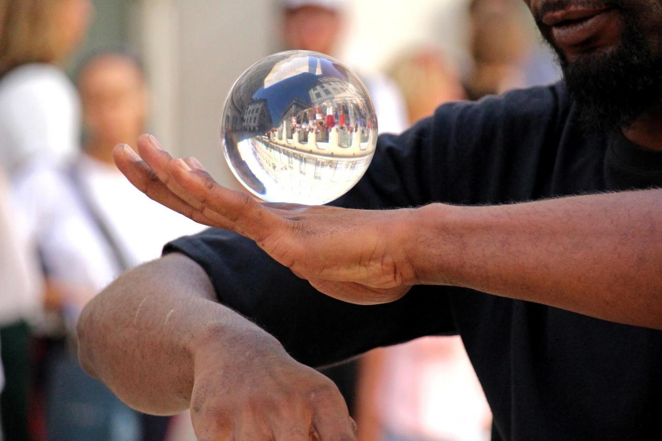 Ein Mann balanciert eine Glaskugel auf seinem Handrücken