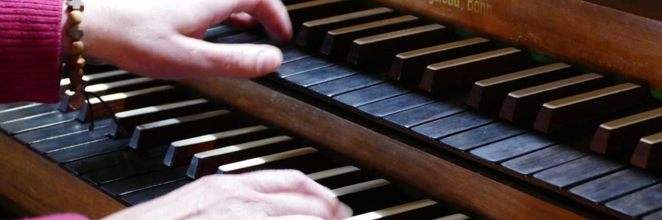 Hände spielen auf einer Orgel mit mehreren Klaviaturen.