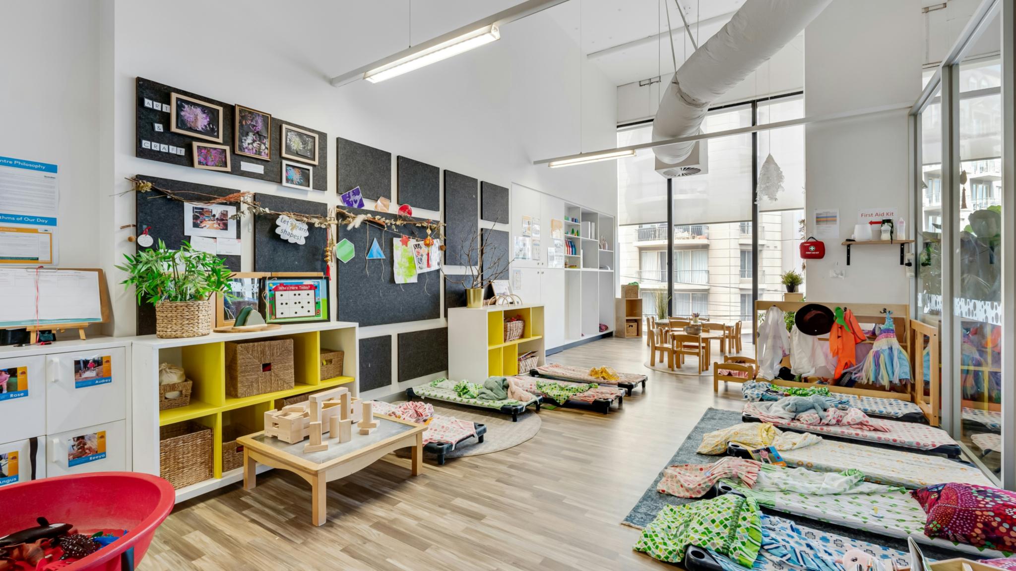 Ein Raum eines Kindergartens mit vielen Möbeln und vielen Fenster.