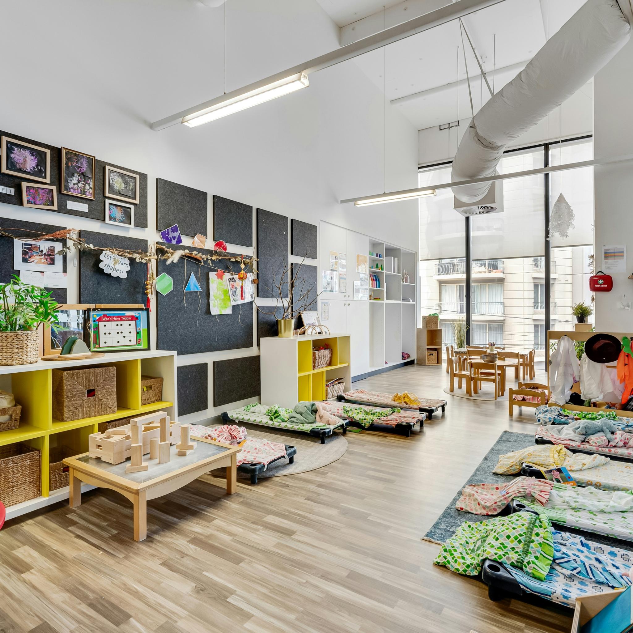 Ein Raum eines Kindergartens mit vielen Möbeln und vielen Fenster.