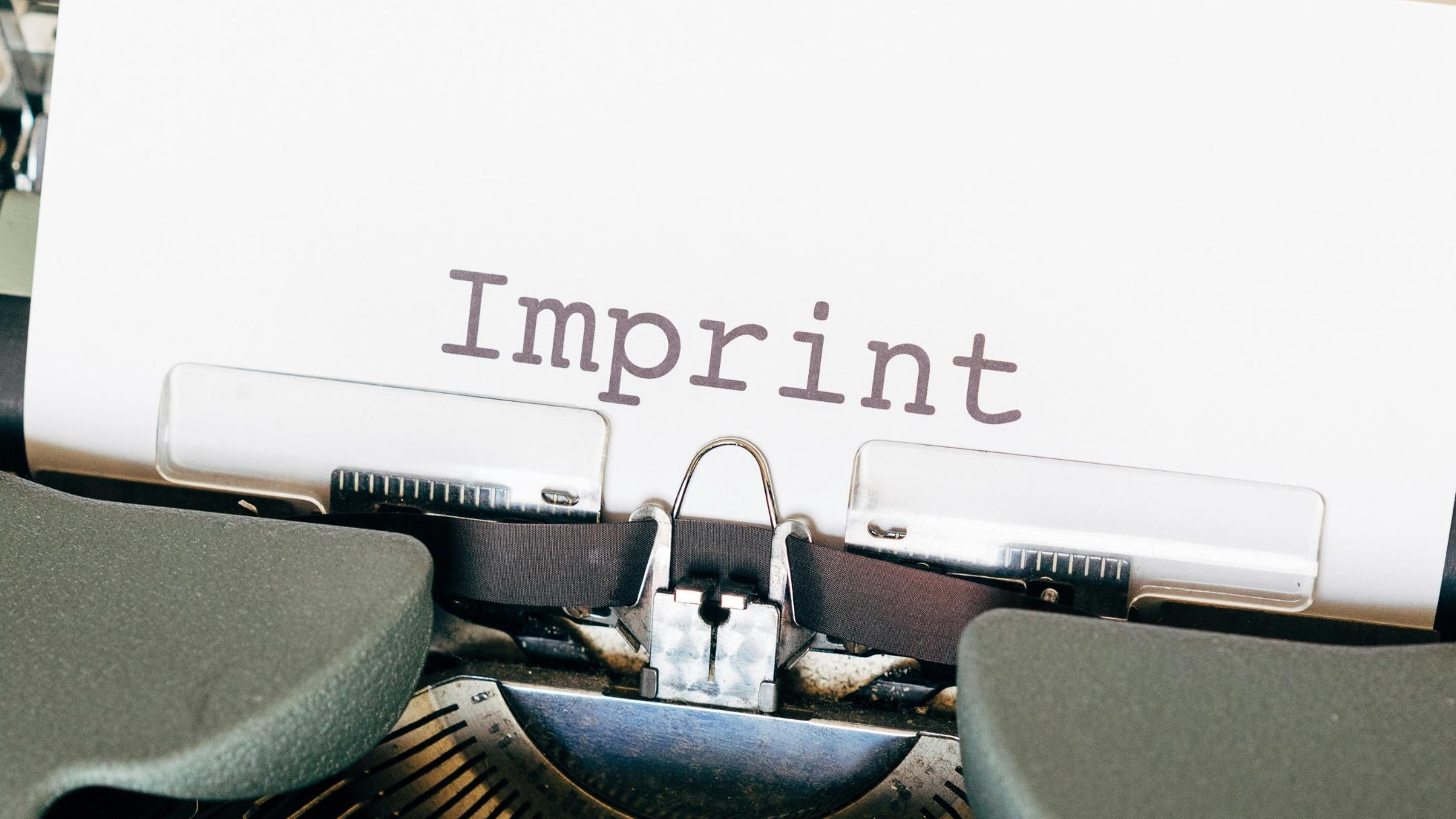 Auf einem Zettel, der in einer alten Schreibmaschine eingespannt ist, steht das Wort Imprint