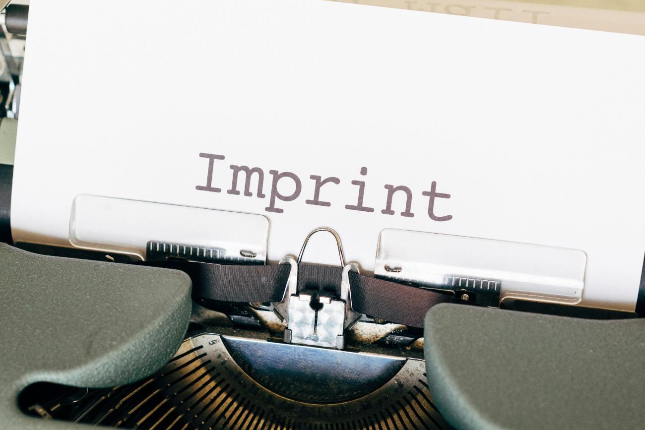 Auf einem Zettel, der in einer alten Schreibmaschine eingespannt ist, steht das Wort Imprint