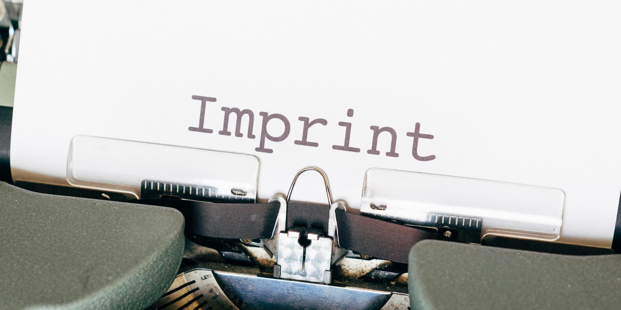 Auf einem Zettel, der in einer alten Schreibmaschine eingespannt ist, steht das Wort Imprint