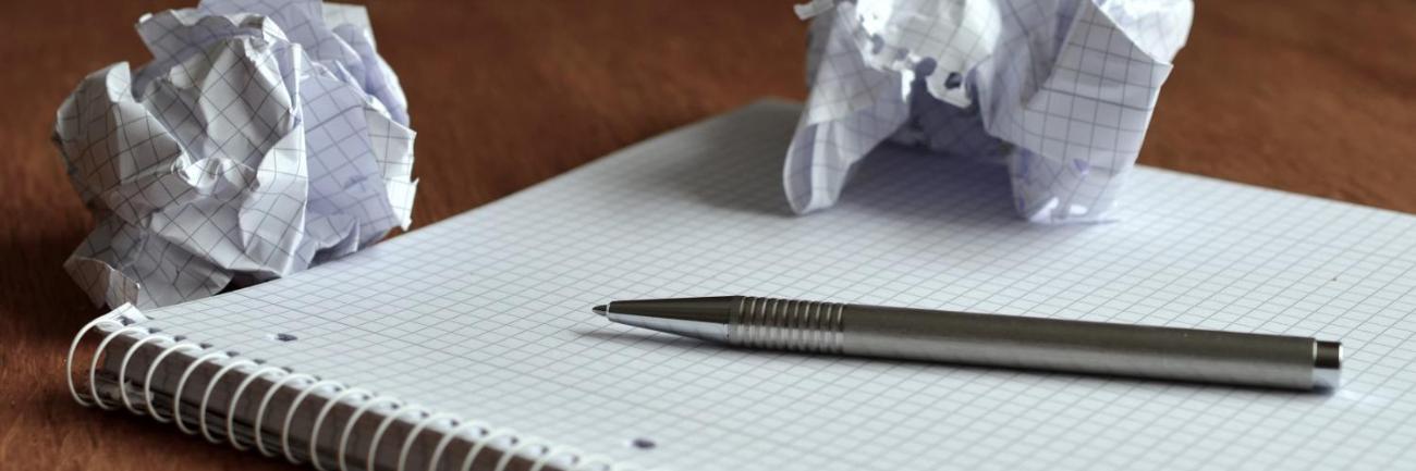 Ein Block mit einem Stift und zwei zerknüllten Blättern Papier