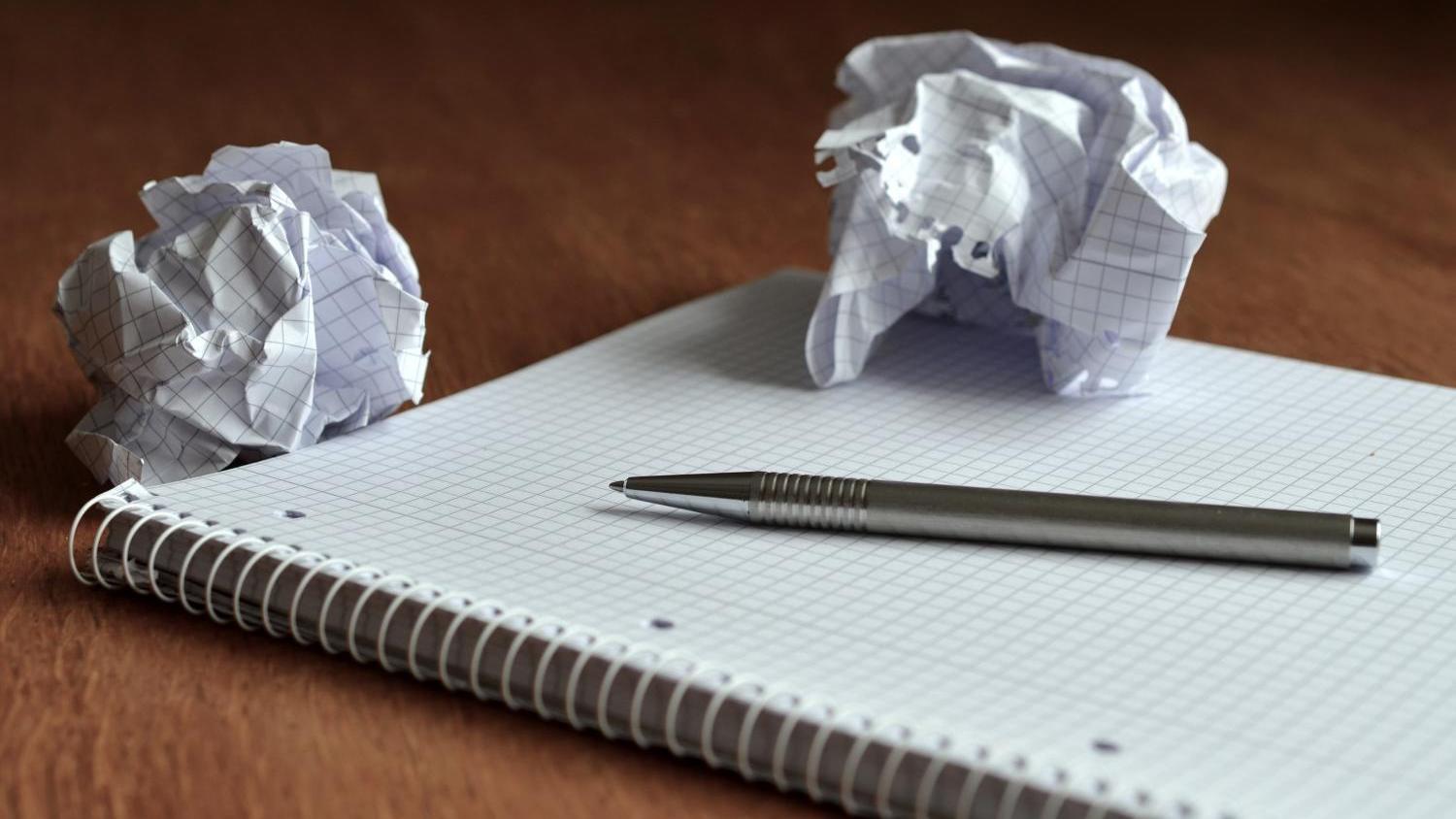 Ein Block mit einem Stift und zwei zerknüllten Blättern Papier