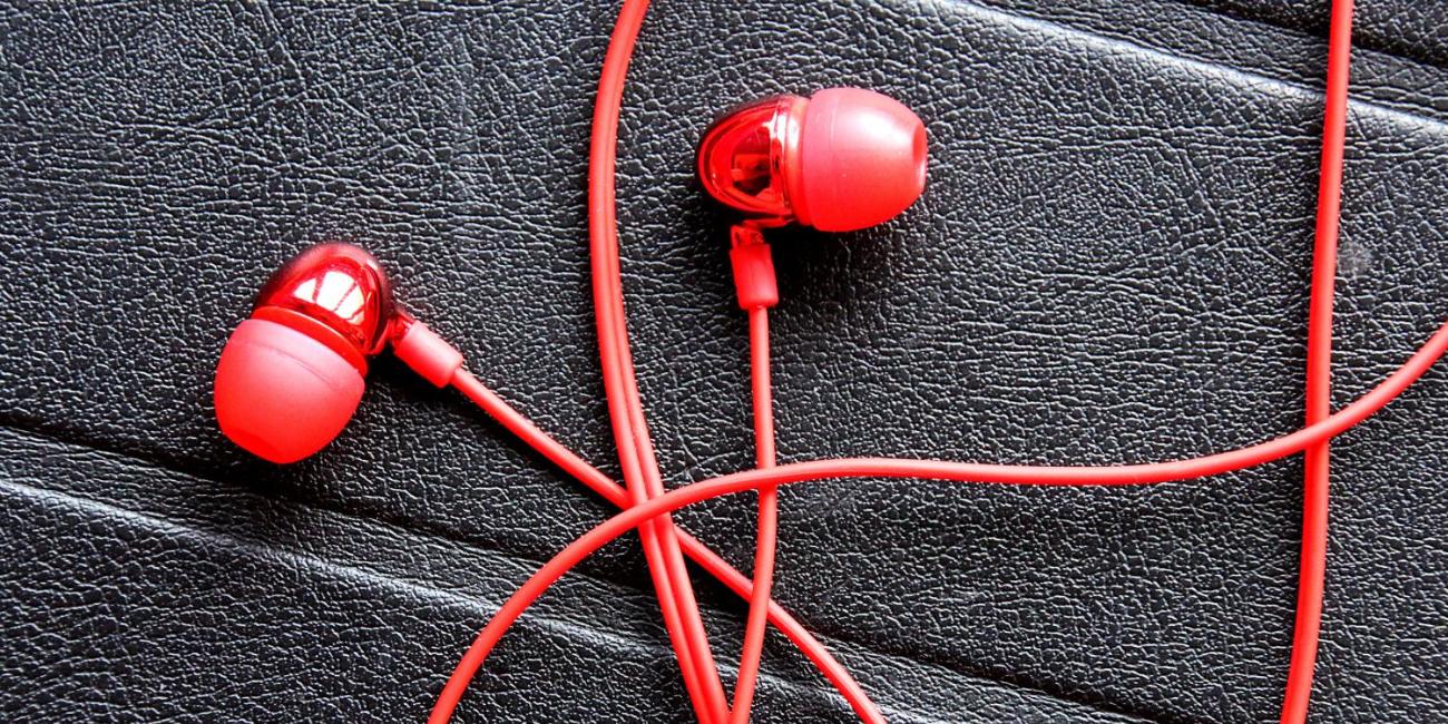 Rote In-Ear-Kopfhörer auf schwarzer, strukturierten Oberfläche.