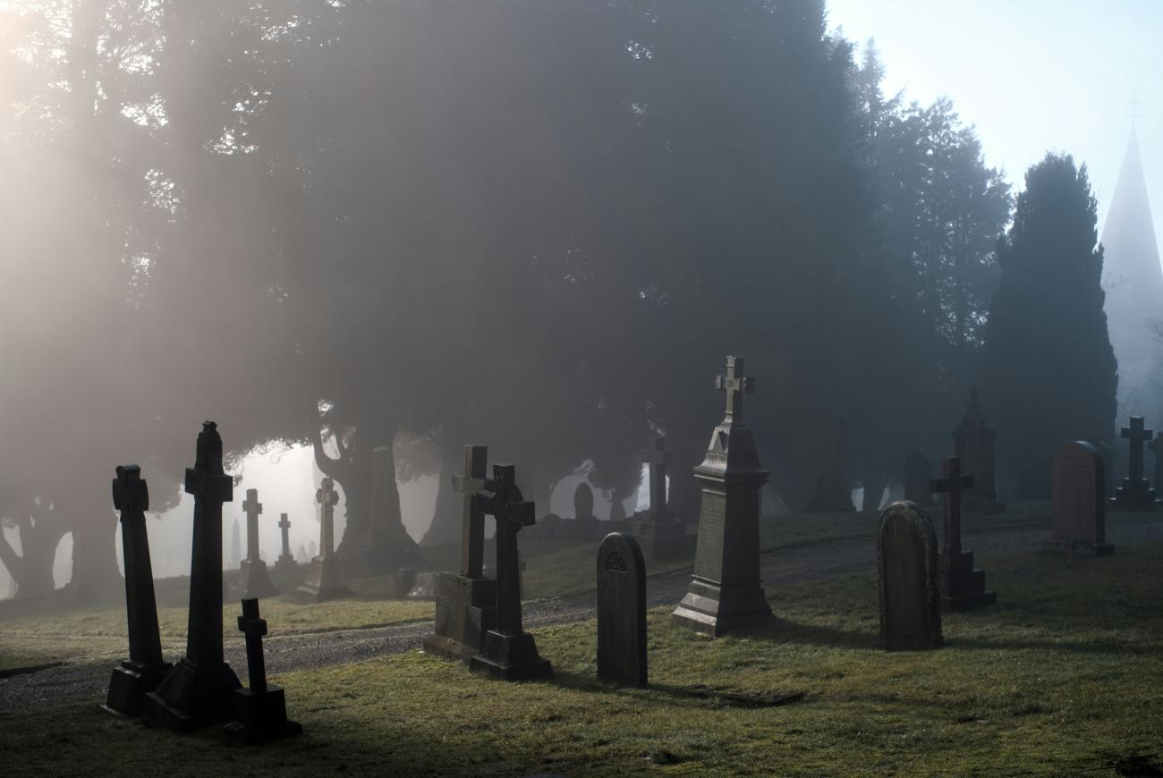 Ein nebliger Friedhof mit Grabsteinen im Vordergrund