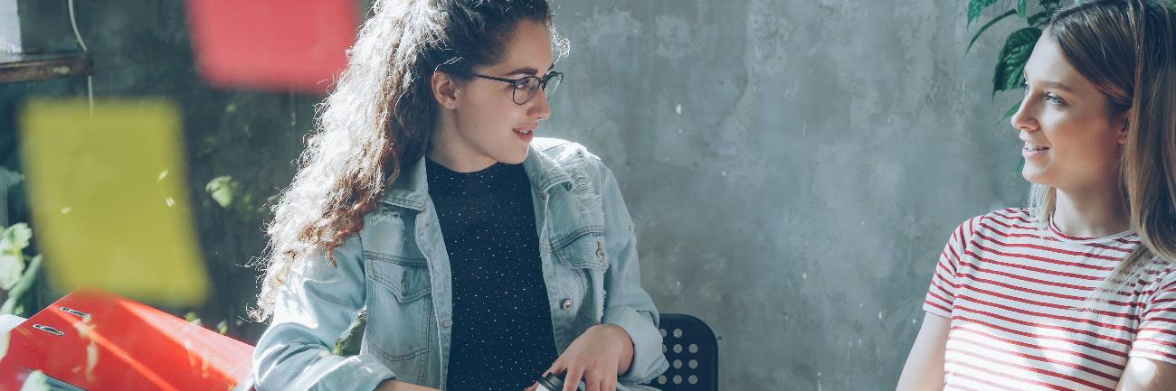 Zwei Frauen unterhalten sich an einem Tisch