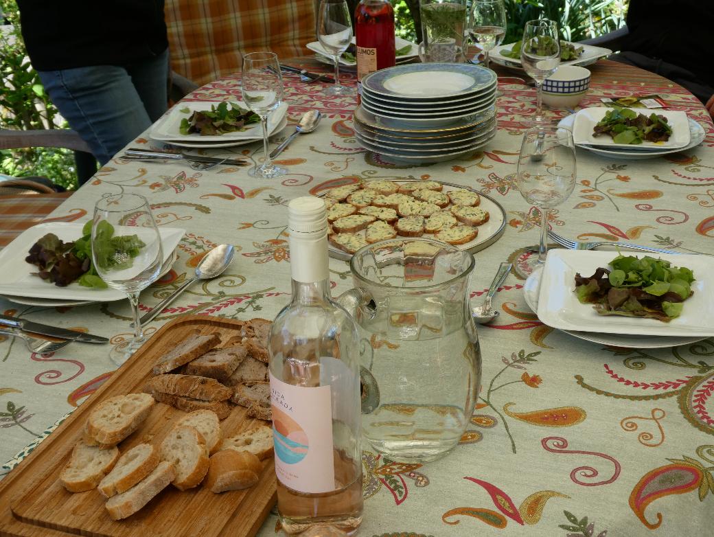 Gartentisch mit Salattellern, Baguette, Wasser und Wein