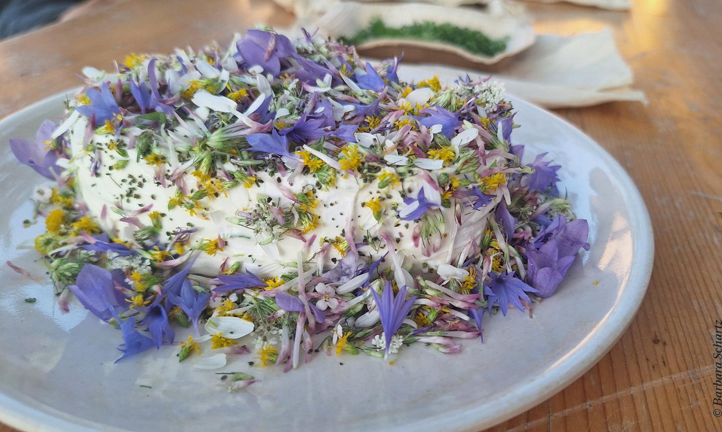 Mit Blüten von Wildblumen dekorierter Camembert