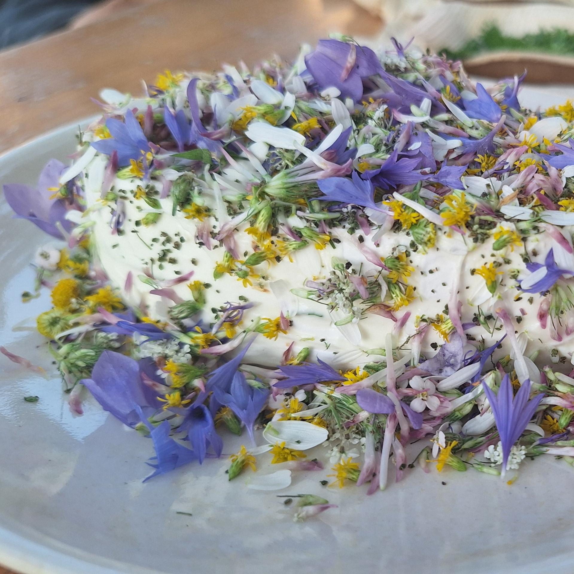 Mit Blüten von Wildblumen dekorierter Camembert