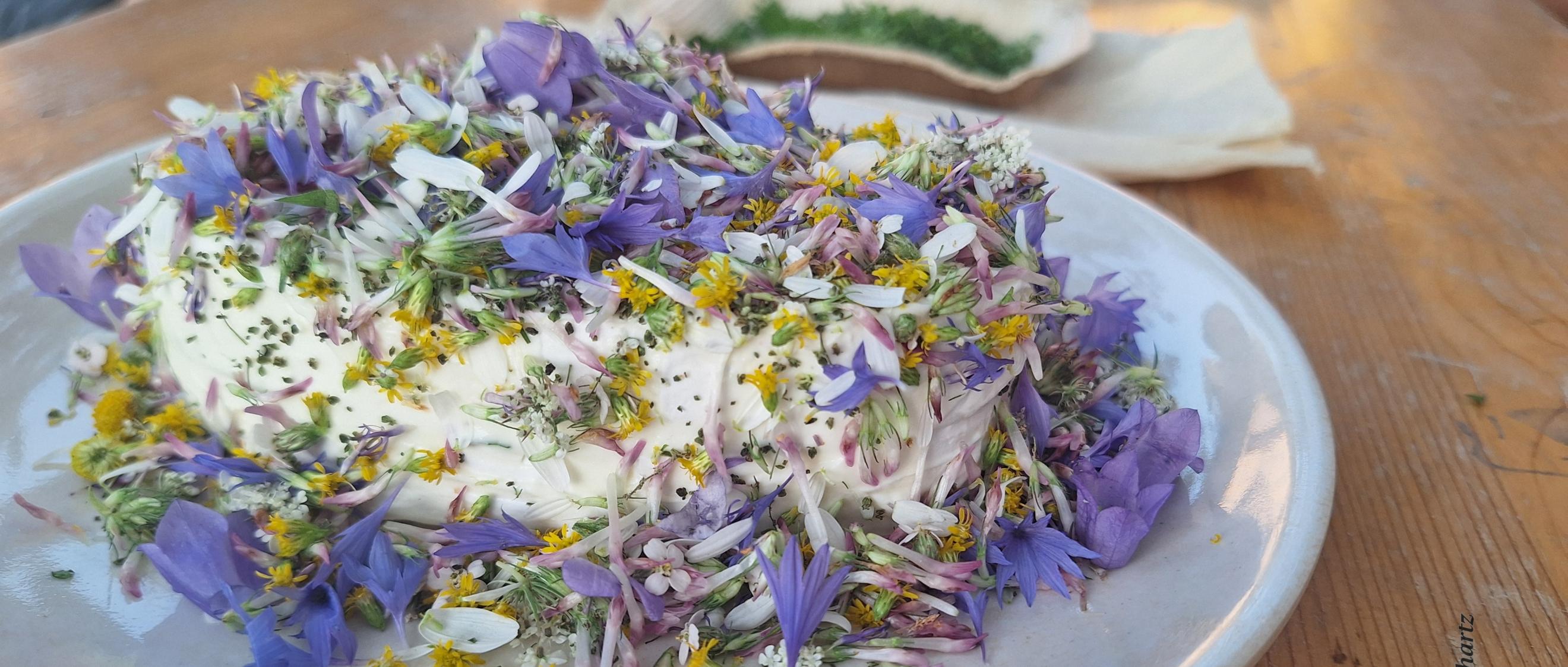 Mit Blüten von Wildblumen dekorierter Camembert