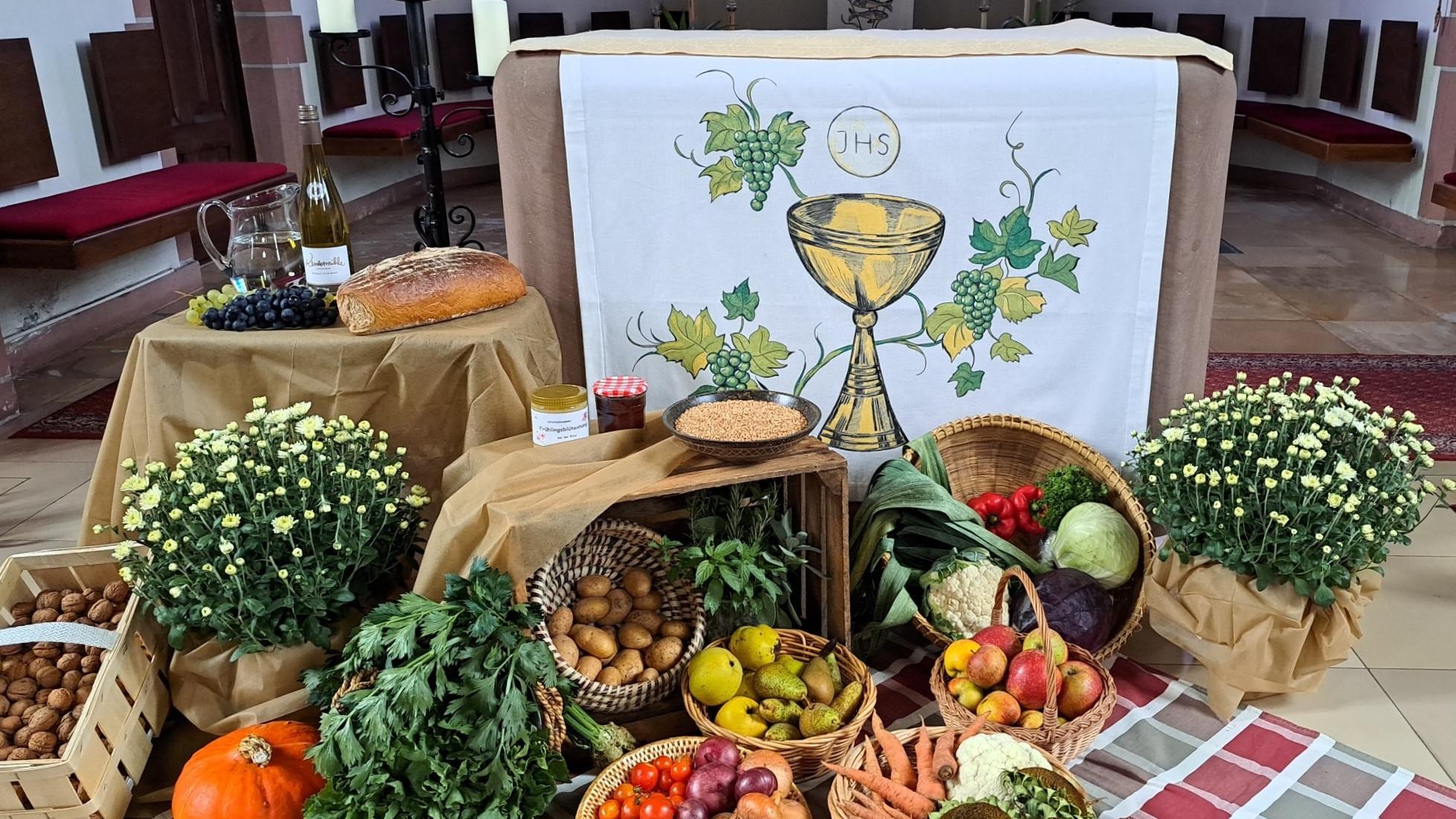 Vor dem Altar der Kirche liegen die Erntegaben in Körben; Gemüse, Obst, Brot und Wein