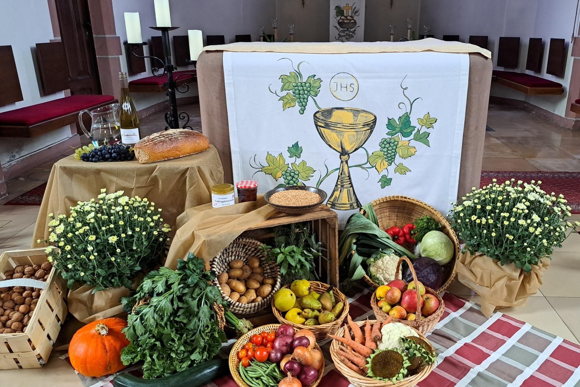 Vor dem Altar der Kirche liegen die Erntegaben in Körben; Gemüse, Obst, Brot und Wein