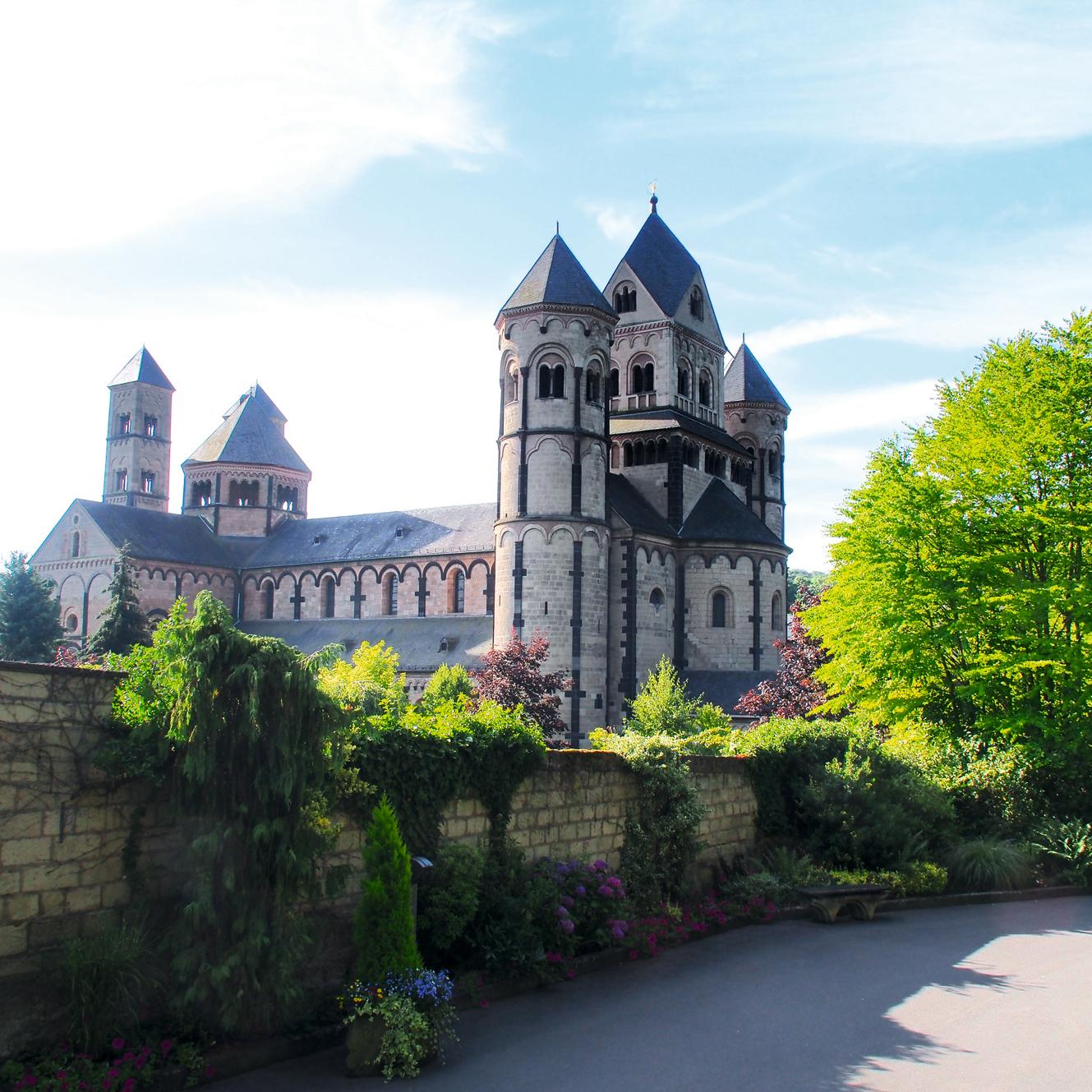 große Kirche mit mehreren Türmen umgeben von einer Mauer und Bäumen