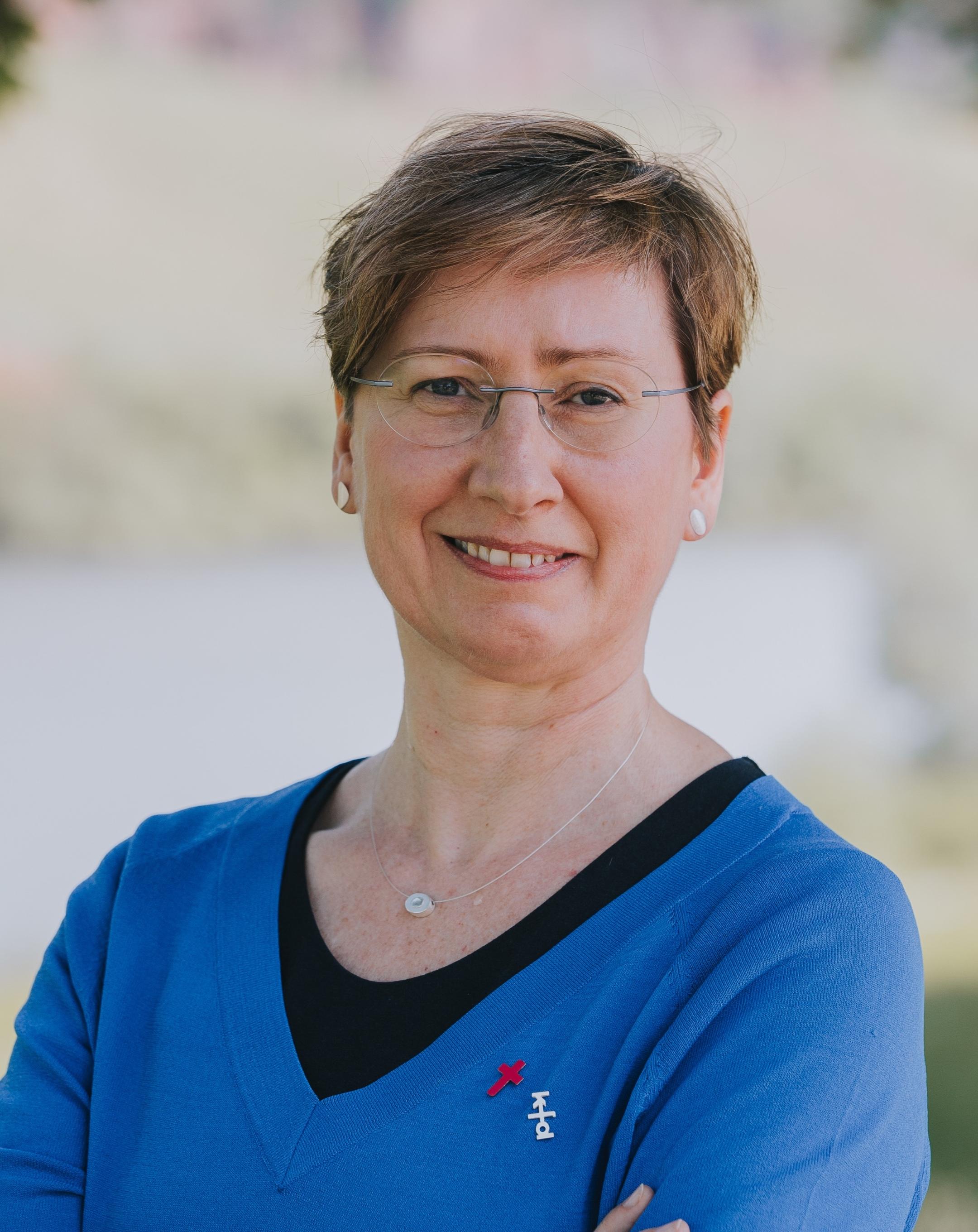 Eine Frau mit Brille und kurzen Haaren lächelt in die Kamera.