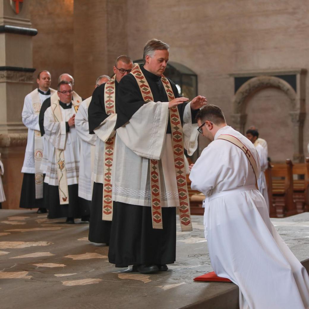 Ein zukünftiger Priester kniet während seiner Weihe im Trierer Dom