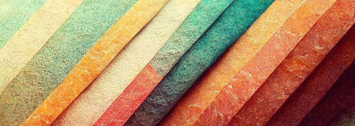 Man sieht verschiedenfarbige Stoff- oder Papierstreifen aneinandergereiht