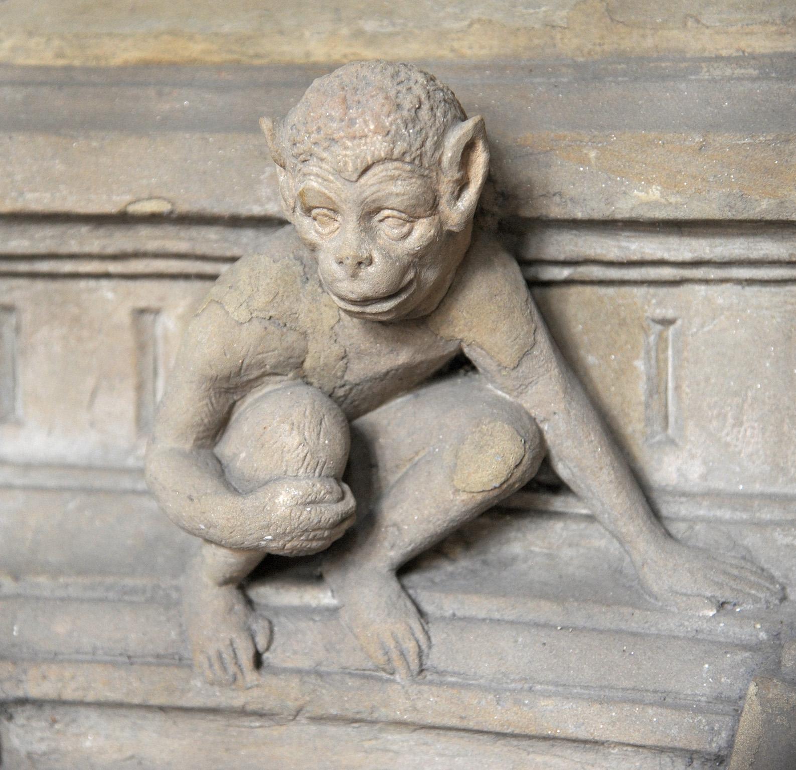 Ein Affe hockt auf einem Sims und stützt sich mit der linken Hand ab